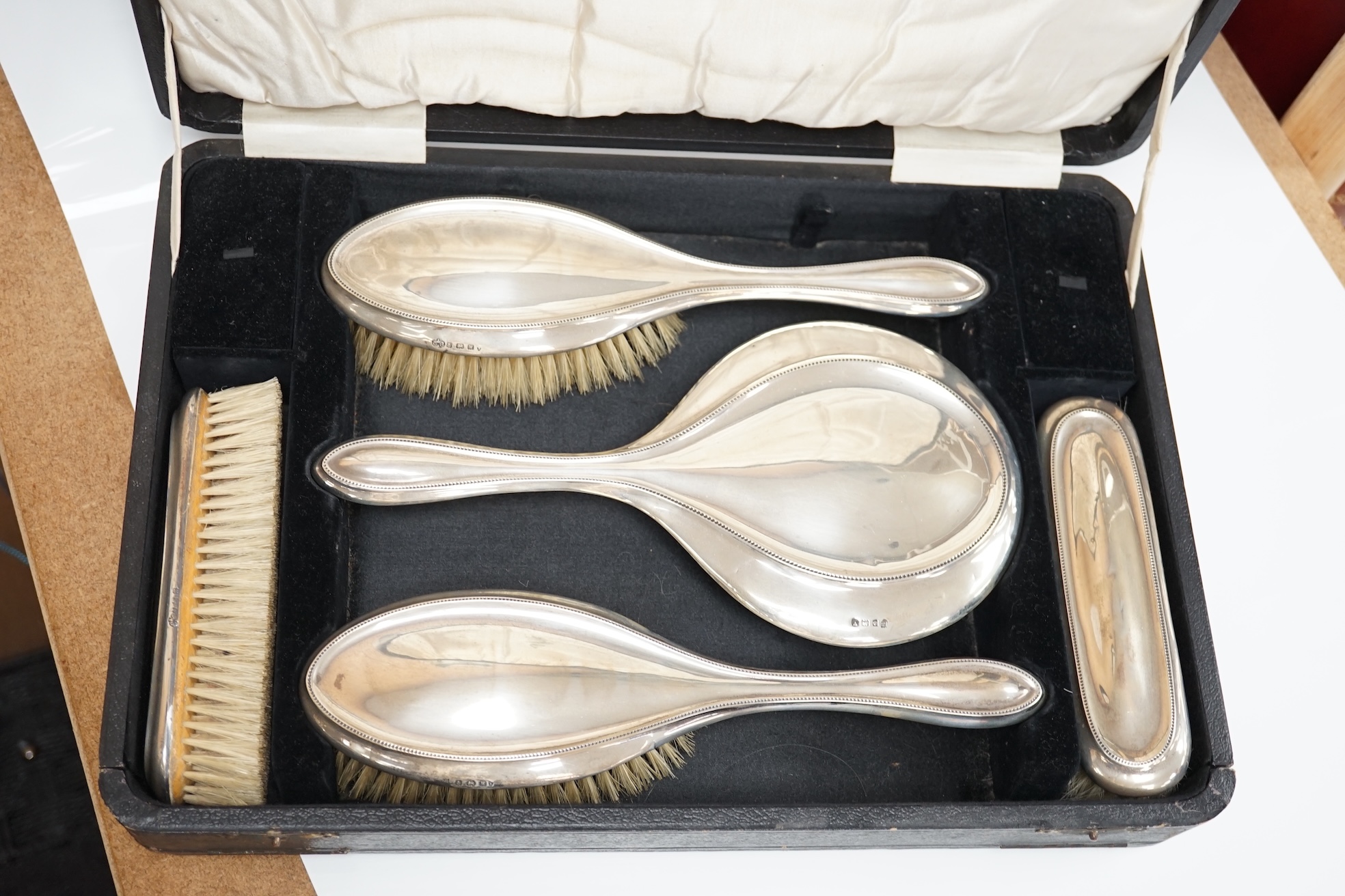 A cased George V five piece silver mounted dressing table mirror and brush set, Charles S. Green & Co, Birmingham, 1920/21. Condition - fair